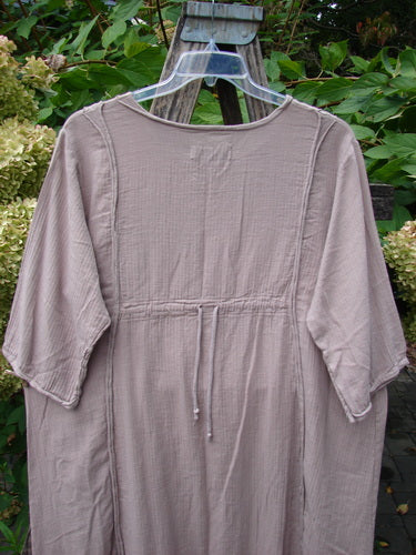 Barclay NWT Textured Batiste Linen Haystack Dress Unpainted Oriel Size 0, features a knee-length, A-line shape with elbow-length sleeves, drawstring waist, and textured fabric, showcased against a floral backdrop.