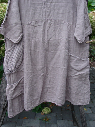 Barclay NWT Linen Calotype Stack Pocket Dress Grow Garden Oriel Size 0, featuring a taupe knee-length design with patch pockets, thinly striped neckline, and three-quarter sleeves, displayed outdoors.