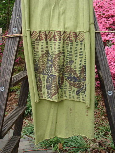 A Barclay Sectional Wrap Scarf in Forest Leaf Peapod, showcasing a green towel with a flower design on a wooden ladder. Perfect for creative self-expression. Dimensions: 20W x 75L. Ideal for styling as a shawl or waist wrap.