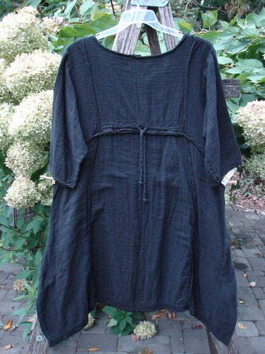 Barclay NWT Gauze Daily Pocket Dress Unpainted Jet Black Size 0: Loose-fitting smock dress with mid-length sleeves, scoop neckline, drawstring under bust, and softly rolled edges, displayed on a trellis with hydrangeas.