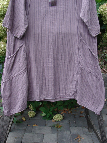 Barclay NWT Gauze Daily Pocket Dress Stripe Rose Earth Size 0 features a loose fit, three-quarter sleeves, rounded neckline, slanted patch pockets, and a subtle vertical stripe texture, displayed outdoors on a wooden frame.