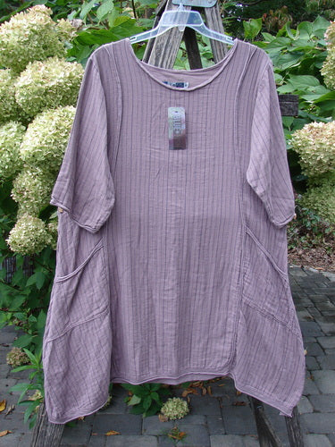 Barclay NWT Gauze Daily Pocket Dress Stripe Rose Earth Size 0 hanging outdoors, showcasing its A-line shape, elbow-length sleeves, large side pockets, and softly rolled edge details against a textured fabric backdrop.