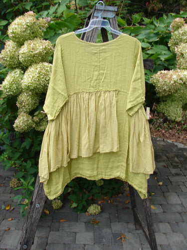 Barclay NWT Gauze Batiste Petal Urchin Flounce Dress in Citron, displayed outdoors on a hanger, showcases a loose fit, flounce accents, and three-quarter sleeves, capturing vintage BlueFishFinder charm.