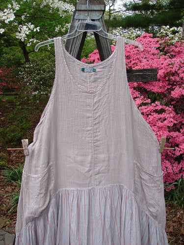 Barclay Gauze Batiste Peasant Jumper hanging on a clothesline, showcasing a blend of cotton gauze and batiste fabrics. Features include a scooped neckline, wrap pockets, and a varying hemline. Size 2.