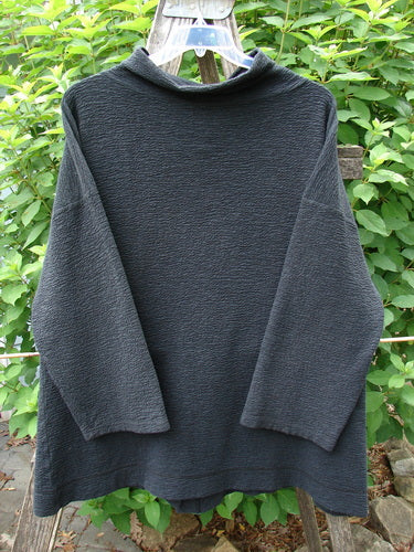 Barclay Crepe Mock Collar Jacket Unpainted Black Size 0, displayed on a fence, highlights its textured crepe fabric, long wide sleeves, and mock neckline, embodying Bluefishfinder.com’s vintage aesthetic.