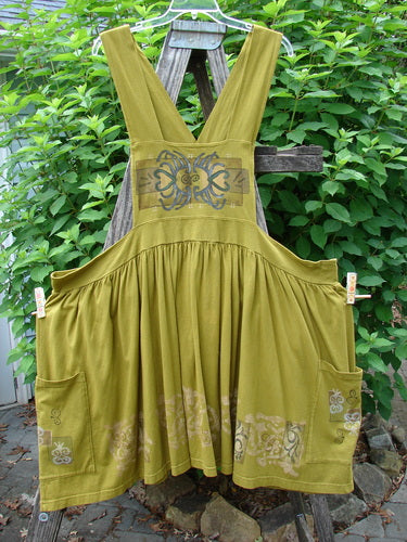 Barclay Overall Jumper Celtic Sun Glazed Tile OSFA displayed on a wooden fence, showcasing its creatively cut bib, crisscross back straps, and full gathered skirt, embodying vintage Blue Fish Clothing style.