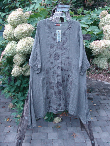 Barclay NWT Linen High Vent Venetian Dress Farm Dark Caper Size 1 displayed on a hanger, showcasing its oval neckline, pinched sleeves, and curvy panels against a garden backdrop, highlighting its artistic design.