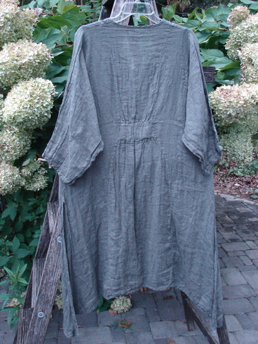 Barclay NWT Linen High Vent Venetian Dress in Dark Caper hangs outdoors, featuring a gathered waist, asymmetrical hem, and pinched three-quarter sleeves, embodying Bluefishfinder's vintage style.