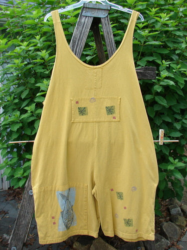 1991 Farmer Brown Overall Pant Jumper Vintage Fish Goldenrod OSFA hanging on a clothesline, showcasing generous shoulder straps, dual front pocket, and extra lower leg panel, epitomizing BlueFishFinder's unique vintage style.