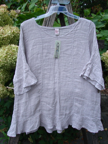 Barclay NWT Gauze Sectional Bias Flounce Top Unpainted Rice Paper Pink Size 1, featuring a lightweight linen texture, petal-accented sleeves, and a flowy A-line shape, displayed on a hanger.