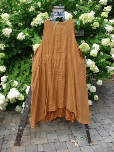 A Barclay Linen Open Front Drawcord Hem Jumper in Squash, featuring a brown dress on a wooden rack.