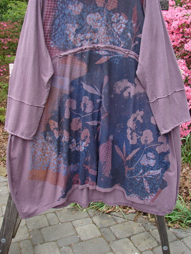 Barclay Cotton Hemp Mock Bell Dress Grid Garden Dusty Plum Size 2, featuring a purple shirt with a pattern. Details include a mock flop collar, varying hemline, raw seams, and grid garden theme. Generous pockets and cozy cuffable sleeves.