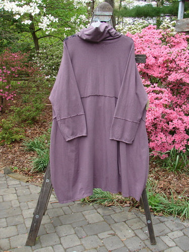 Barclay Cotton Hemp Mock Bell Dress Grid Garden Dusty Plum Size 2 displayed on a wooden stand. Features include a mock flop collar, varying hemline, raw seams, and grid garden paint details.