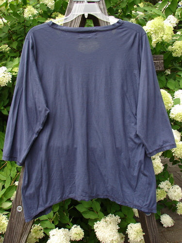 A close-up image of a Barclay Tissue Raglan V Neck Layering Top in Navy Sky. The top features 3/4 length sleeves, a soft V-shaped neckline with a little flutter, and a slight hourglass shape. The varying hemline adds a touch of uniqueness to this tee-like top.