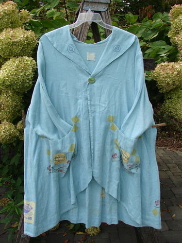 1999 Linen Breeze Jacket Tea & Cherries Spring OSFA: An artisan-style, hooded powder-blue coat with a single button closure, large pockets with motifs, and stitched swirl details, ideal for cool, creative layering.