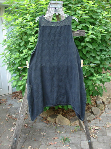 Barclay Linen Lace Two Pocket Pinafore Metallic Travel Black Size 0 displayed on a wooden rack, featuring a rounded neckline, deep arm openings, varying side hem, and lace details.