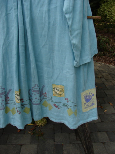 1999 Linen Breeze Jacket Tea & Cherries Spring OSFA draped on a wooden support, showcasing its signature tea and cherry theme with a classic sailor collar, oversized pockets, and a distinctive hemline.