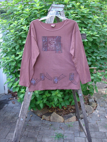 Barclay Long Sleeved Studio Tee Celtic Wind Loam Size 0 displayed on a wooden rack, showcasing its straight boxy shape, thinner flattened neckline, and whimsical character from Bluefishfinder.com.