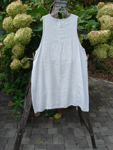 Barclay NWT Linen Image Pinafore Pocket Overpiece Floral Burst Dew Size 0 draped on rustic ladder, showcasing loose-fitting silhouette with dual drop pockets and varying side hem against a garden backdrop.