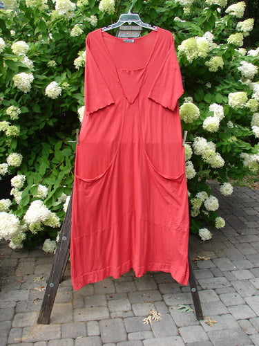 Barclay Reverse Triangle Sectional Dress Unpainted Geranium Size 2: A red dress on a rack with three-quarter length sleeves, curly edgings, and a longer narrowing shape. Features a single lower batiste hem flutter and deep exterior front drop bushel pockets. Made from organic cotton.