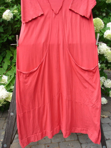 A red dress with a triangular insert, three-quarter length sleeves, and deep front drop pockets. Made from organic cotton. Size 2.