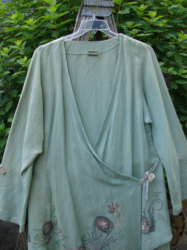 Barclay Viscose Long Ribbon Side Tie Jacket Garden Folly Kelp Size 0 displayed on a hanger, showcasing its flowing hemline, single ribbon closure, and intricate seam details, embodying Bluefishfinder.com's vintage elegance.