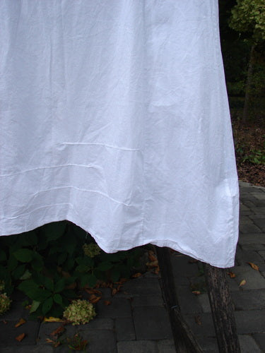 Barclay NWT Retro Pinch Shift Unpainted White Buttercup Size 1 displayed on a wooden trellis, highlighting its rounded neckline and wide A-lined hem with vertical sectional panels and pinched accents.