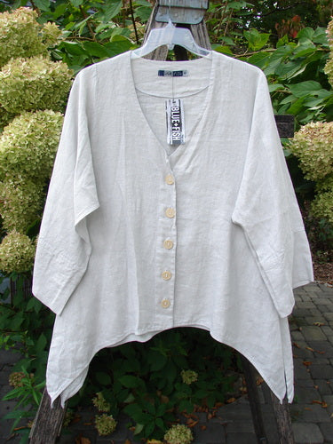 Barclay NWT Linen Basque Cardigan Unpainted Dove Size 0, featuring a deep V-neck, mother-of-pearl buttons, loose fit, and mid-length sleeves, hanging on a wooden rack outdoors amidst greenery.