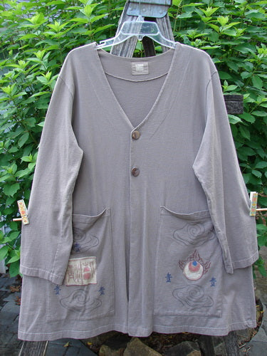 1999 Triangle Jacket Far Eastern Shale Size 1 on a rack, features long sleeves, deep V neckline, two oversized painted pockets, and a drawcord back, embodying vintage Blue Fish creativity.