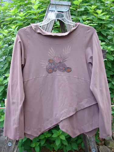 Barclay Cotton Lycra Tiny Button Cross Over Top Galaxy Dusty Burgundy Size 0, showcasing a unique crossover button wrap, vertical gathered sides, and lower sleeve lettuce edgings, hanging on a clothes rack.