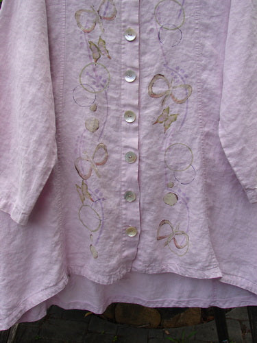 Barclay Linen Shell Button Drawcord Cardigan Butterfly Orchid Size 0 features a varying hemline, shell buttons, and butterfly garden theme paint, showcasing its flowy A-line shape with a drawcord backline.
