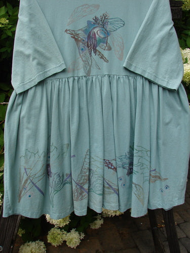 Barclay Flower Garden Tunic Dress Dragonfly Aloe Size 2: A blue dress with a butterfly and bird design, featuring a ceramic button front, pleated skirt, and a rounded neckline.