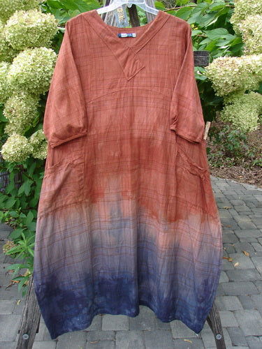 Barclay NWT Flannel Cross Over Blue Moon Pocket Dress Terra Ombre Plaid Size 0, displayed outdoors, showcases a plaid-like texture with an ombré dye effect, transitioning from rusty orange to deep indigo.