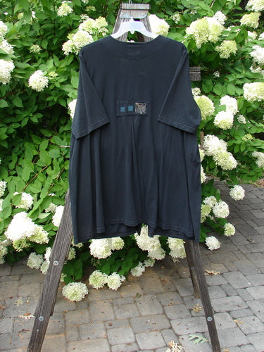 2000 Double Decker Pocket Top Forest Flower Black Size 2: A black t-shirt with two oversized pockets stacked on top of each other. Features a pleated back line, signature Blue Fish patch, and forest flower theme paint. Length is 35 inches.