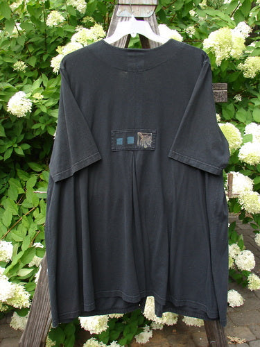 A black t-shirt with two oversized pockets stacked on top of each other. Features a pleated back line, signature Blue Fish patch, and forest flower theme paint. Size 2.