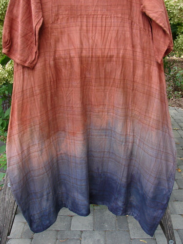 Barclay NWT Flannel Cross Over Blue Moon Pocket Dress Terra Ombre Plaid Size 0, featuring a loose fit and gradient-dyed pattern from rust-red to deep indigo, displayed on a garden path.