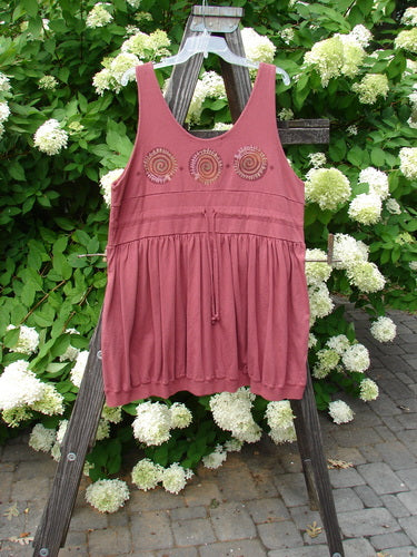 1996 Amusement Jumper Circle Track Ember Size 1: A pink dress with spirals on it, featuring a draw cord back, elastic accented front side pockets, and a ribbed hemline.