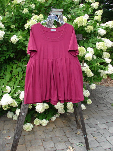 Barclay Boxcar Dress with rear blossom design in cranberry color, size 2. Made from medium weight cotton jersey. Features include a squared double paneled deeper neckline, empire waist seam, wide full pleats, and a lower flair. Measurements: Bust 50, Waist 52, Hips 58, Hem Circumference 120, Length 37 inches.