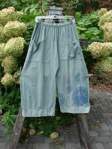 Barclay Flutter Bottom Crop Cargo Pant Medallion Vine Size 0, displayed on a hanger outdoors, features loose-fit, elastic waistband, oversized front pockets, and subtle circular prints near the hem.