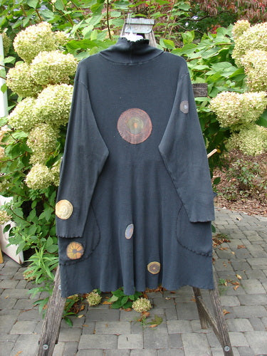 Barclay Patched Thermal Exterior Stitch Side Pocket Tunic Off Black Size 2, featuring a high collar, flared hem, and multicolored circular appliqués, draped over a wooden stepladder outdoors.