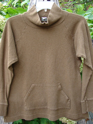 2000 Wool Funnel Neck Raglan Top Unpainted Pebble Smaller Size 1, showcasing a loose turtleneck and kangaroo pocket, hung on a hanger outdoors, reflecting vintage Blue Fish Clothing's creative and timeless style.
