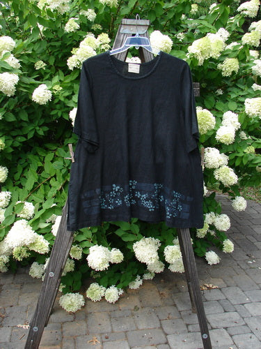 2000 T Top Floating Florals Black Size 2: A swinging A-line black shirt on a clothes rack with continuous florals and side vents.