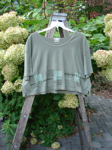2000 City Side Crop Tee Top Navigation Border Park Size 2, displayed on a wooden ladder outdoors, features a minimalist graphic near the hem, showcasing Blue Fish's creative, vintage style with vented sides and swingy shape.