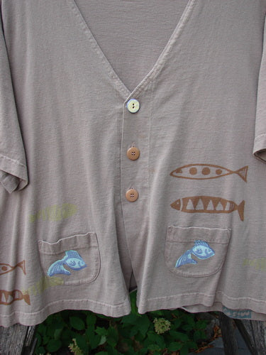 1999 Tiny Pocket Top Fishie Riverbed Size 2: Short-sleeved V-neck top with mismatched buttons, patch pockets featuring blue fish motifs, and a swingy cropped A-line shape. Made from mid-weight organic cotton.
