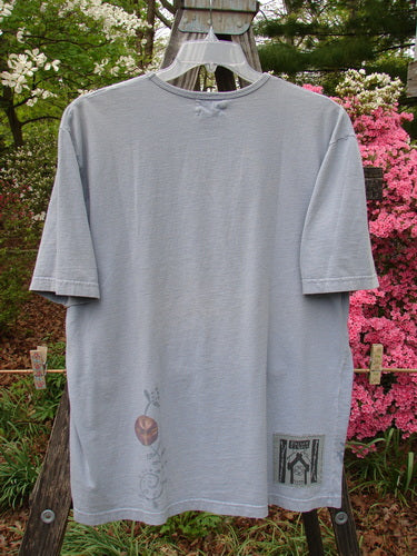 1999 Short Sleeved Tee Floral Medallion Bluestone Size 1 displayed on a clothes rack, showcasing its medium weight organic cotton fabric and unique floral medallion design.