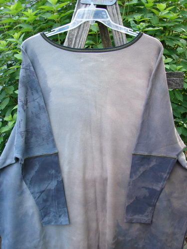 The Barclay NWT Thermal Contrast Revival Top Tunic Tree Line Amethyst Smoke OSFA is displayed on a clothes rack, showcasing its ribbed accents, rounded neckline, and unique tree line theme.