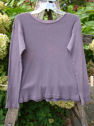 1998 Pointelle Long Sleeved Under Top Unpainted Modena Size 1 displayed on a clear hanger against a rustic wooden backdrop, highlighting its ribbed texture and cozy, rolled neckline in an outdoor garden setting.