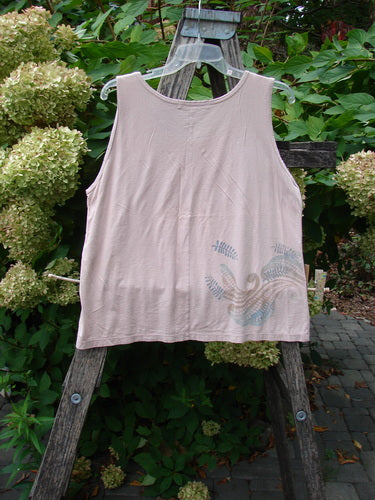 Barclay Batiste Tank Top Fern Wind Blush Size 1 on a clear hanger, displaying a sleeveless design with a stylized bird graphic near the hem, against a garden trellis backdrop.