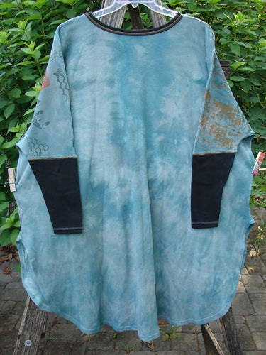 Barclay Thermal Contrast Revival Top Farm Turq OSFA, featuring black ribbed sleeves and a rounded neckline, displayed on a rack. The top has a distinctive farm theme design with generous, flowing dimensions.