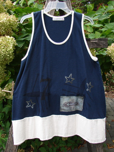 1998 8 Ball Tunic Games Crew Blue Size 1, featuring navy-blue organic cotton with white trim, star motifs, and abstract patch. Scoop neckline, A-line shape, and racerback style showcased against outdoor foliage.